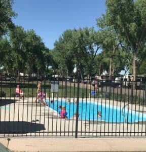 Guests enjoying the outdoor swimming pool at Loveland RV Resort on a sunny summer day.