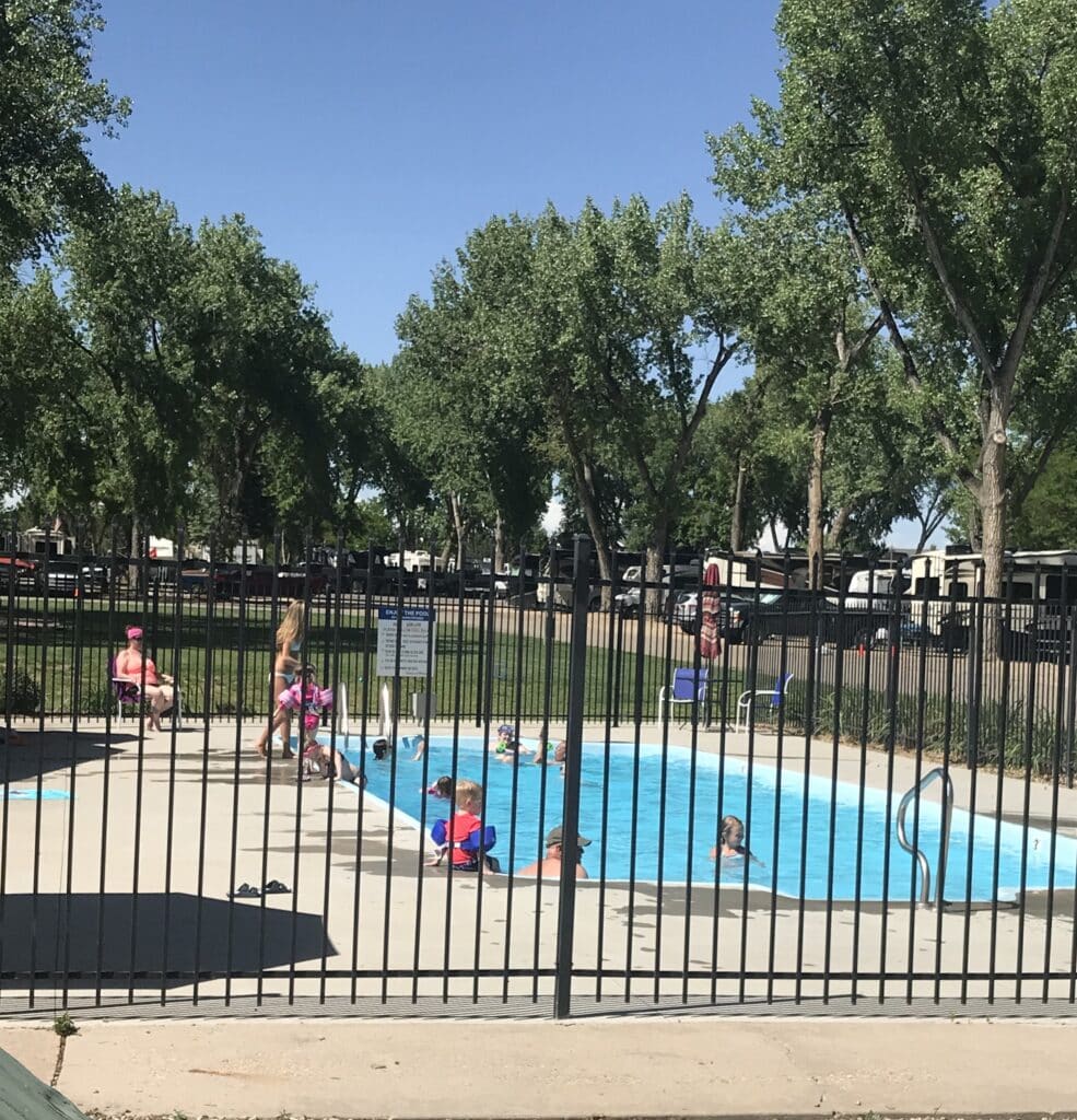 Guests enjoying the outdoor swimming pool at Loveland RV Resort on a sunny summer day.