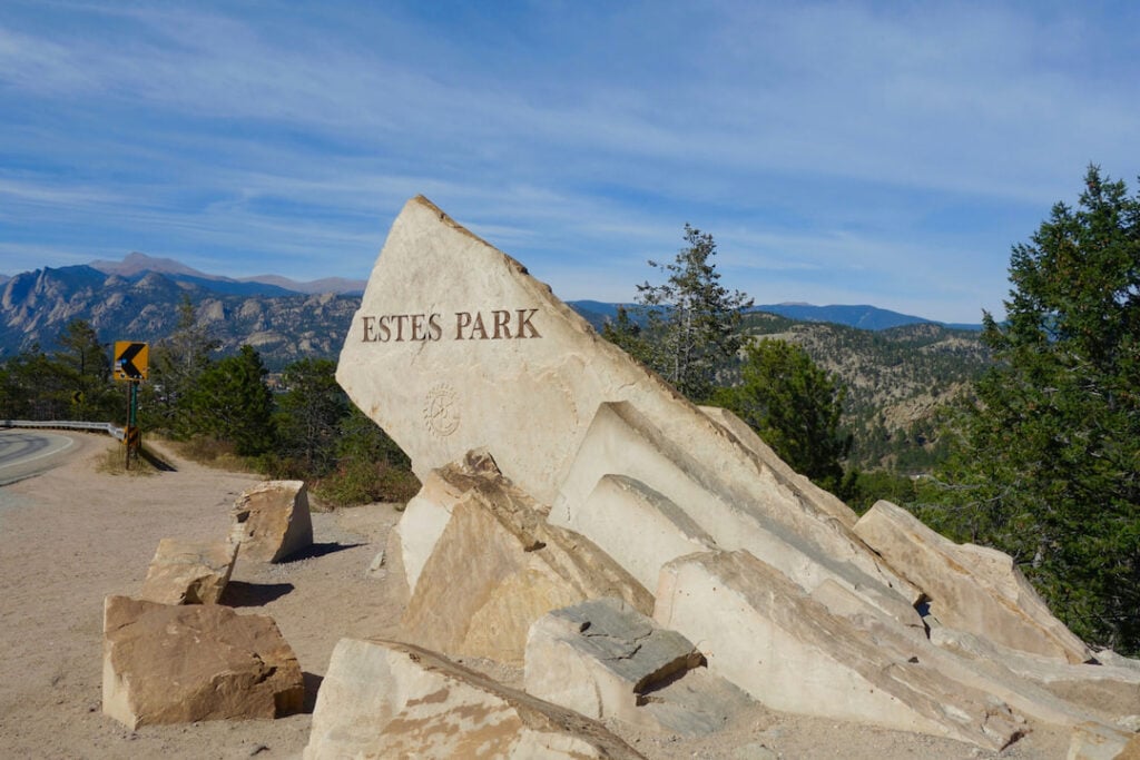 Estes Park stone sign with Rocky Mountain views.